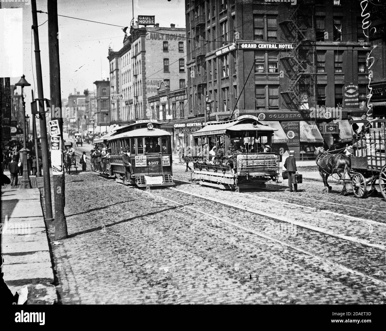 Streetcars with passengers moving along Madison Street at its intersection with Canal Street in front of the Grand Central Hotel, Chicago, Illinois. Stock Photo