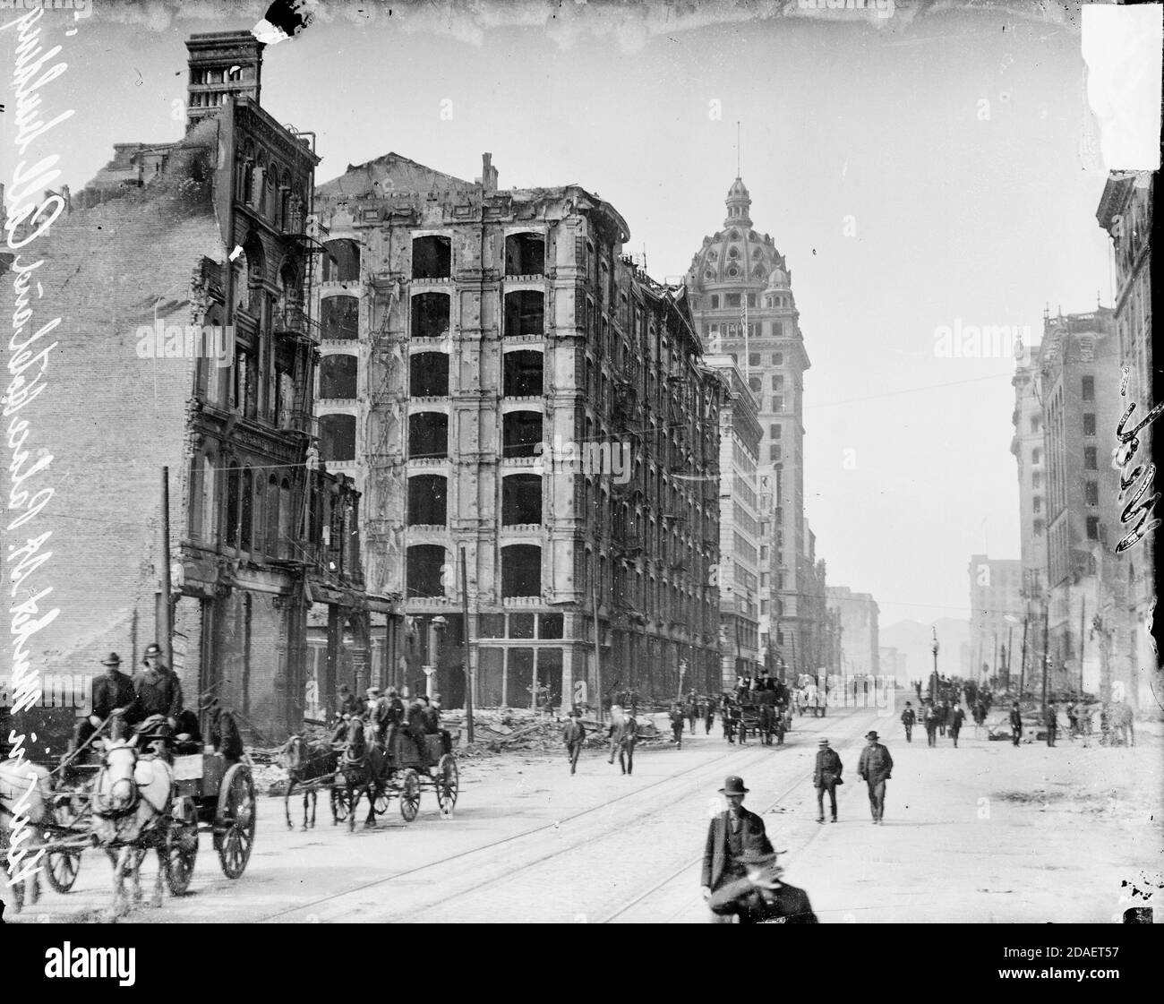View of pedestrians and horse-drawn vehicle traffic moving along Market Street in San Francisco, California, past ruins after the 1906 earthquake. Stock Photo