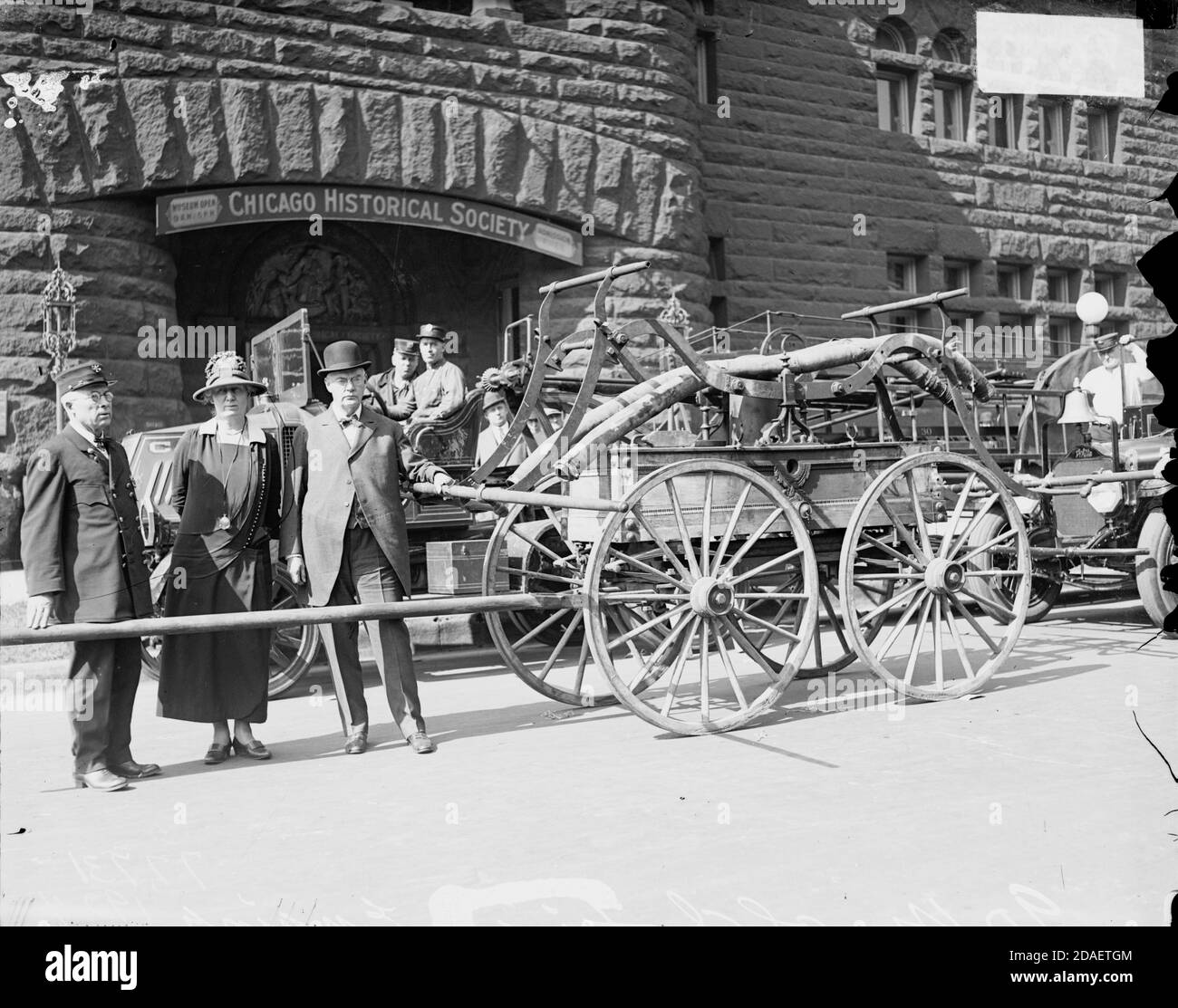 Fireman and other people standing with old-fashioned fire engine in front of the Chicago Historical Society Stock Photo