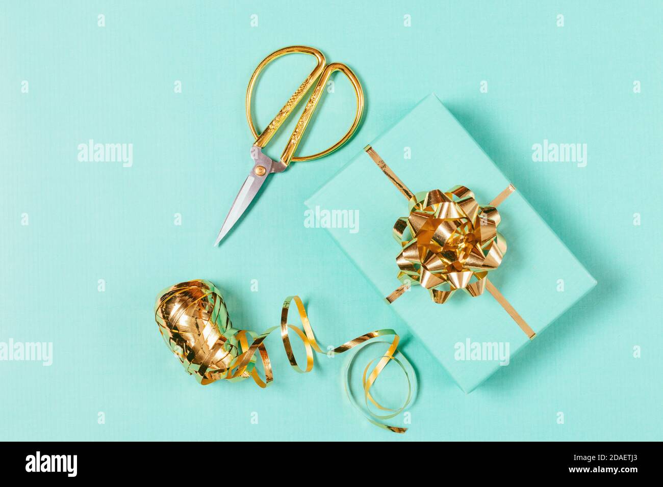 Top view of gift wrapping process with box, golden ribbon and scissors