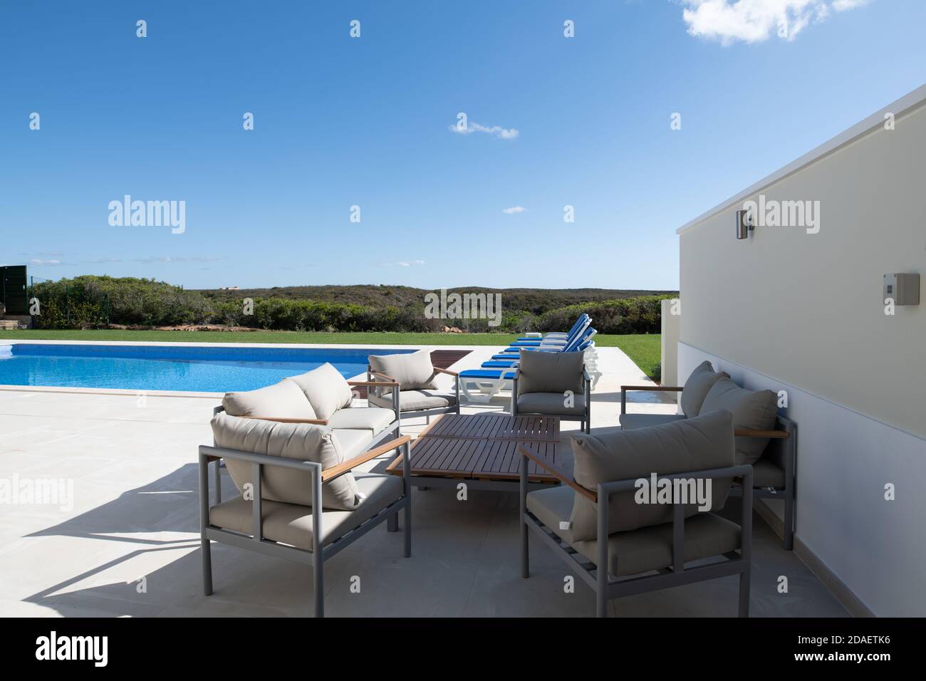 patio seating area in the garden of a luxury holiday villa with swimming pool in the background Stock Photo