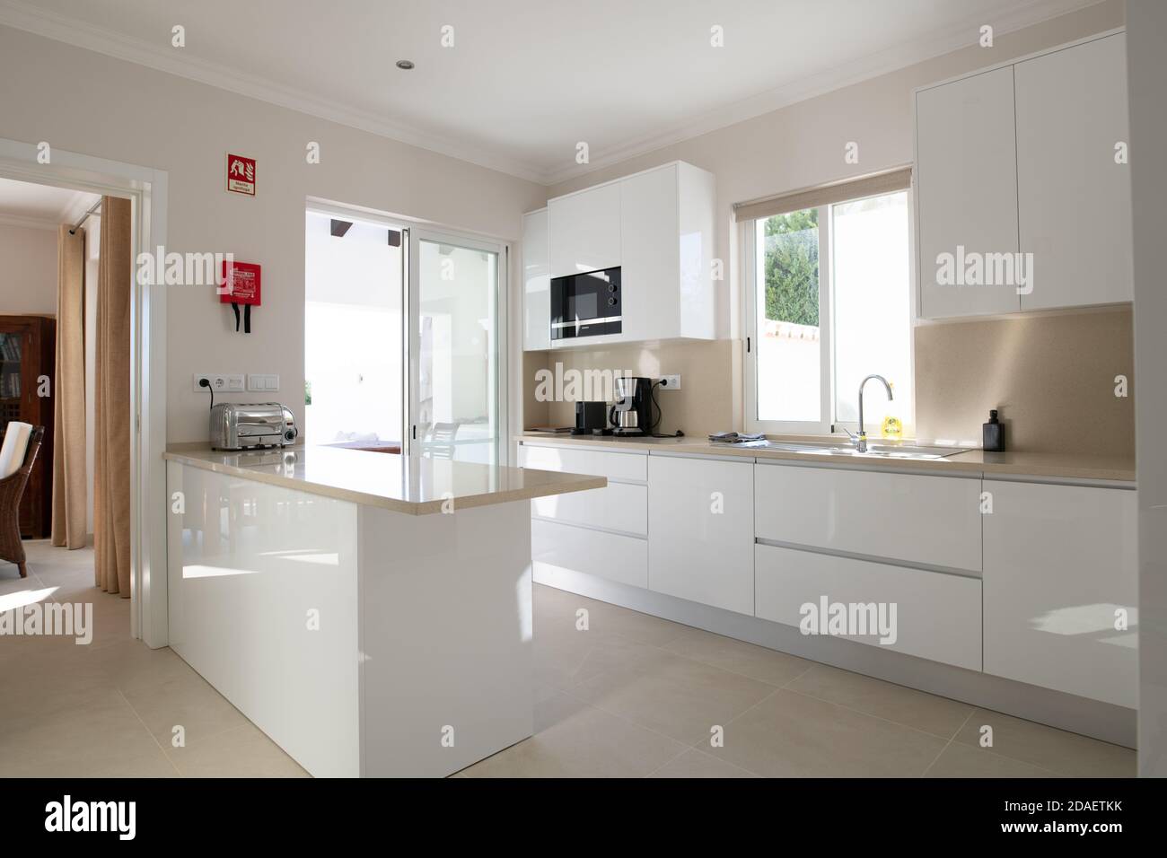Brand new modern kitchen with white cabinets and beige stone counter top and ceramic tiled floor Stock Photo