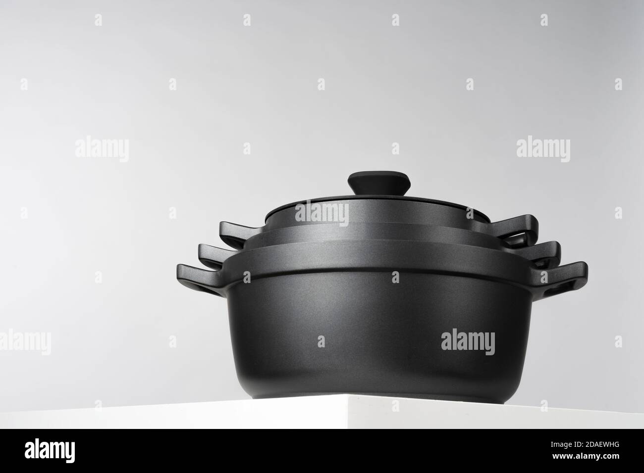 Black cooking pots on grey background front view Stock Photo - Alamy