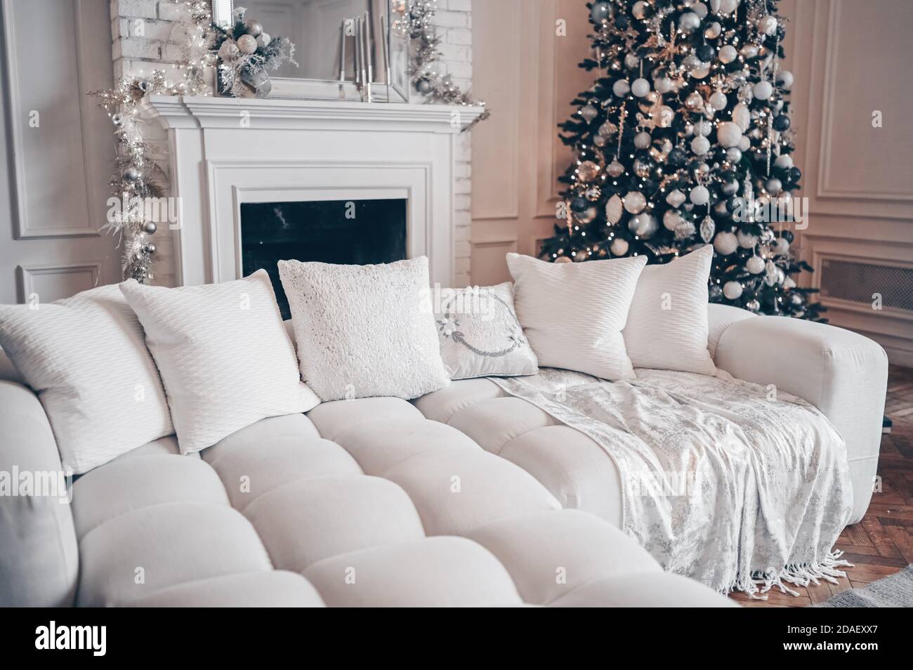https://c8.alamy.com/comp/2DAEXX7/decorated-christmas-tree-with-gifts-in-white-classic-living-room-interior-with-new-years-holiday-sparkling-garland-a-bright-room-with-white-modern-cozy-sofa-and-fireplace-2DAEXX7.jpg