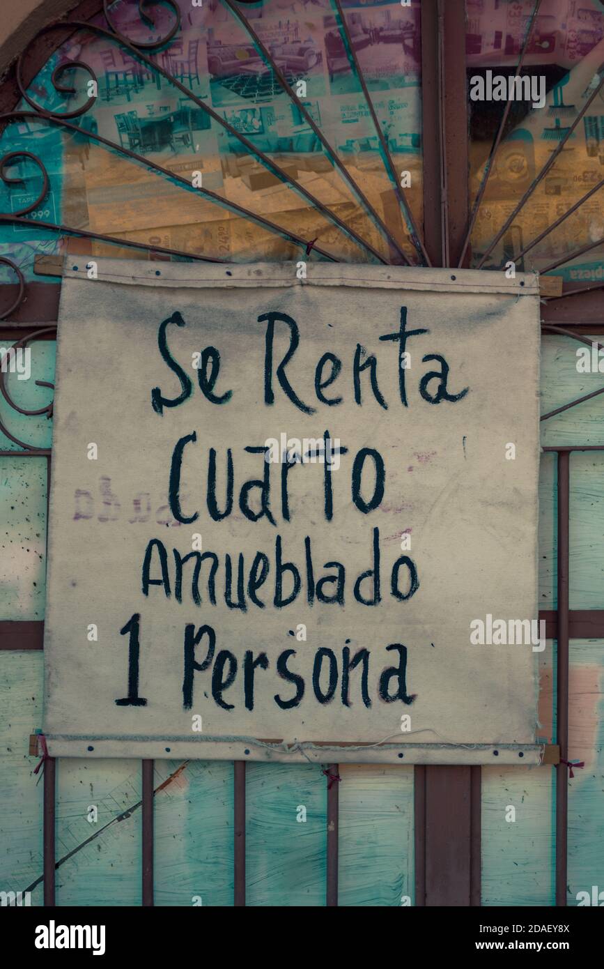 In Mexico, a handwritten sign in a window with bars advertises a furnished room for rent for one person. Stock Photo