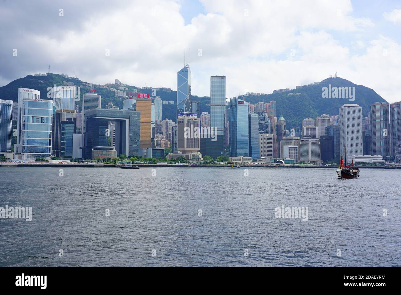 HONG KONG -29 JUN 2019- A Chinese junk ship passes in the Victoria harbor in front of the modern Hong Kong skyline. Stock Photo