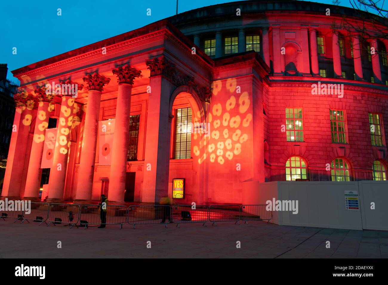 Armistice Day Commemoration during lockdown. Manchester Central Library, UK lit with red light and poppy design. Blurred people. Public building Stock Photo