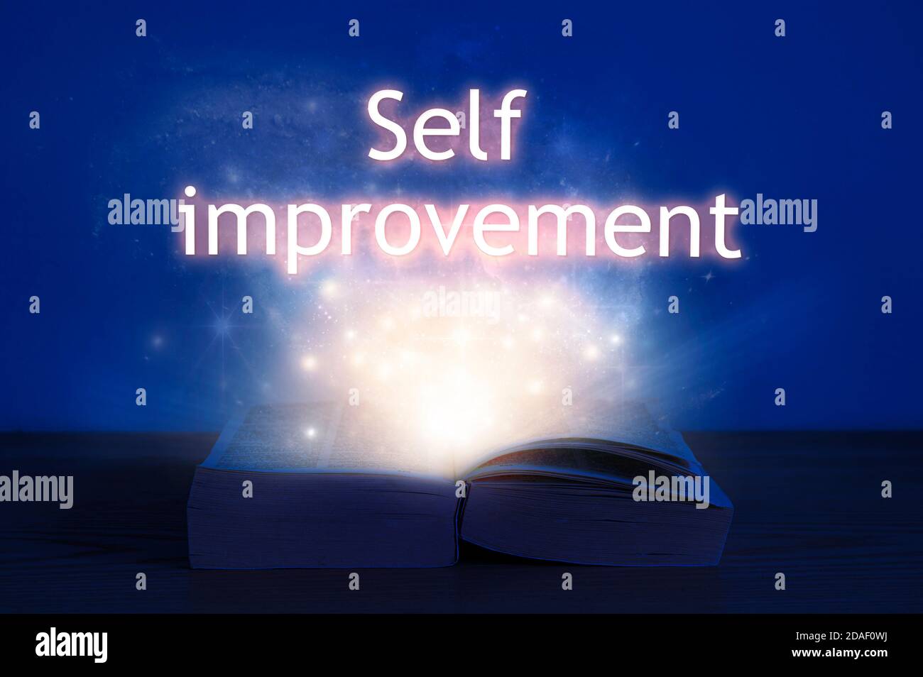 Open book with self improvement inscription. Light coming from open book with words self improvement. Stock Photo