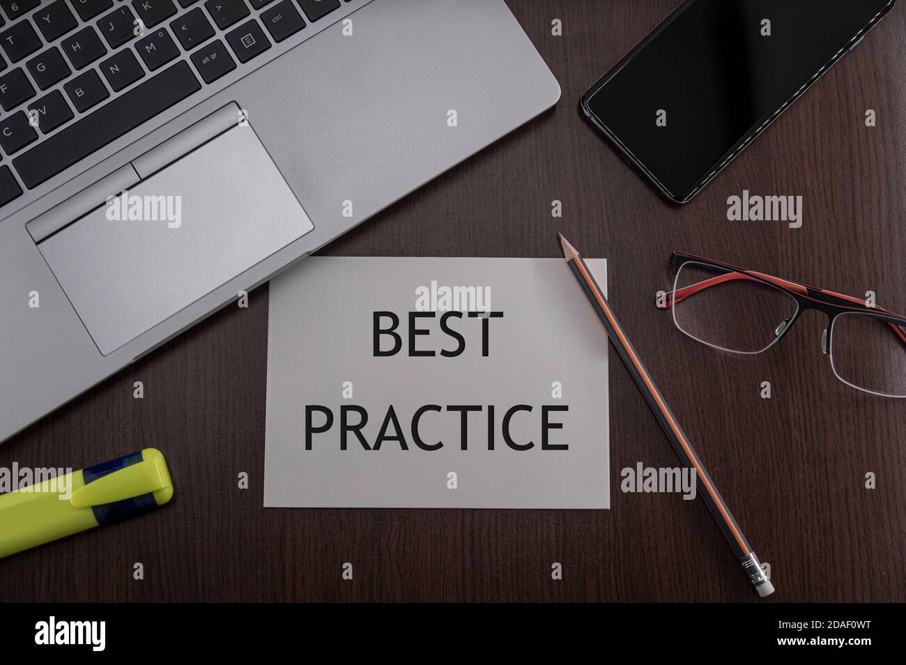 Top view of laptop, phone, glasses and pencil with card with inscription best practice. Business concept. Stock Photo