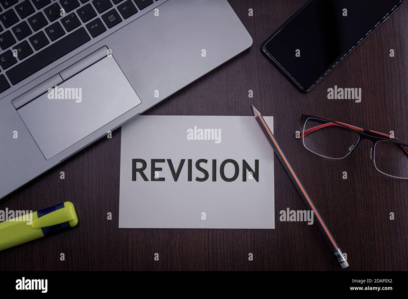 Top view of laptop, phone, glasses and pencil with card with inscription revision. Business concept. Stock Photo