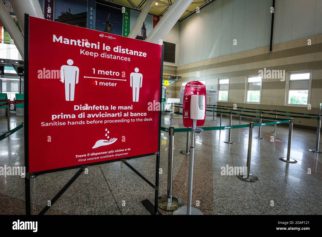 Sign at Olbia airport in Sardinia, Italy, reminds passengers to keep social distance and disinfect hands during coronavirus crisis in Italy. Stock Photo