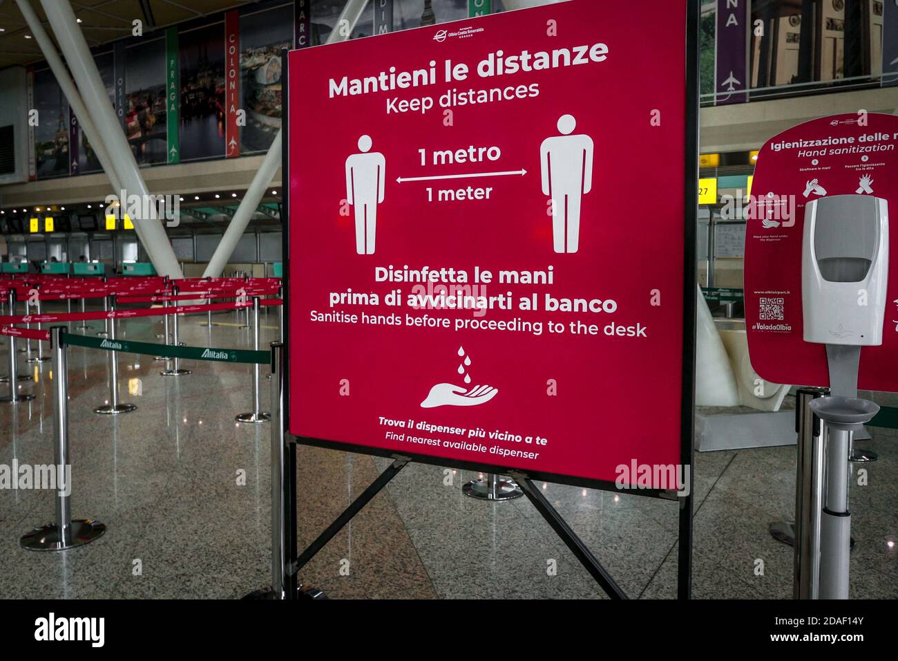 Sign at Olbia airport in Sardinia, Italy, reminds passengers to keep social distance and disinfect hands during coronavirus crisis in Italy. Stock Photo