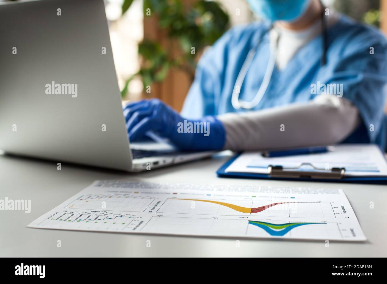 Epidemiologist doctor working on laptop computer,analyzing graphs & charts,COVID-19 Coronavirus global pandemic crisis outbreak,mortality death rate Stock Photo