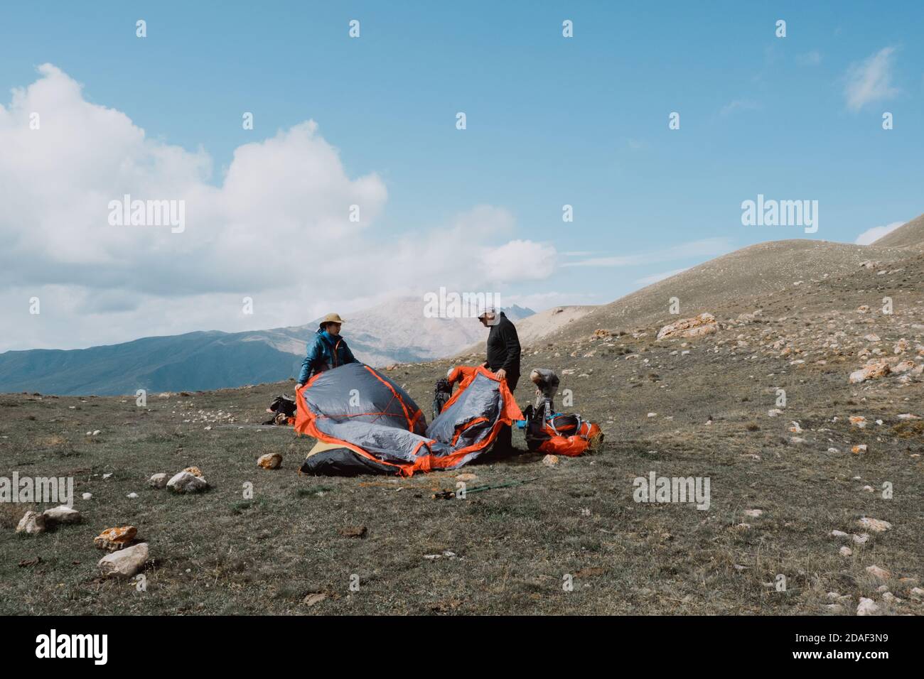 Russia, Dagestan - September, 21, 2020:Two men set up tourist tent on the top of mountain. Stock Photo