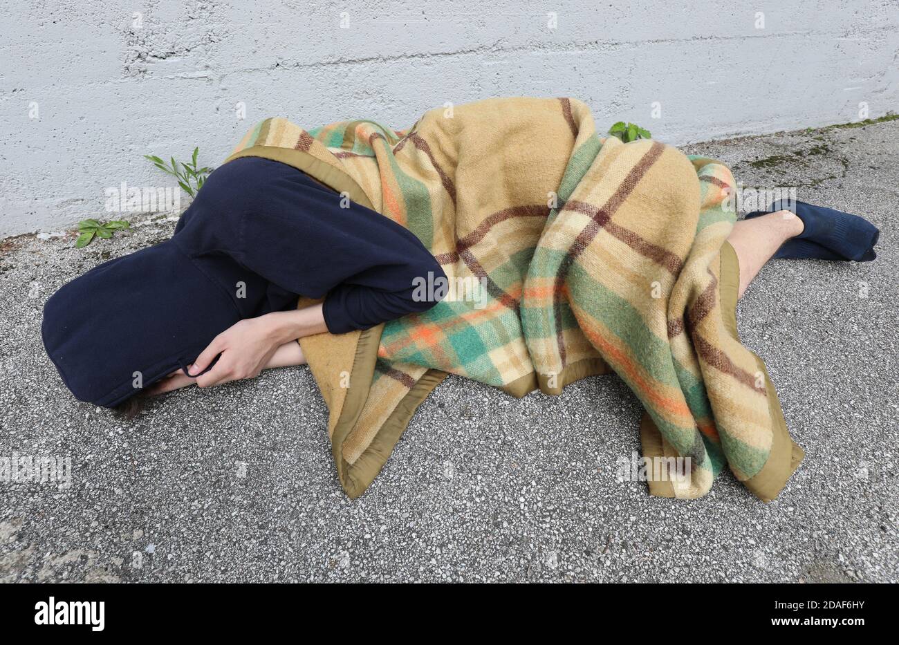 homeless as he sleeps on the floor under a filthy blanket Stock Photo