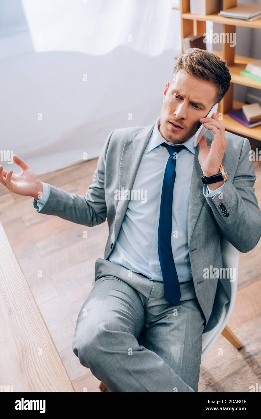 High angle view of businessman in suit talking on smartphone in office Stock Photo