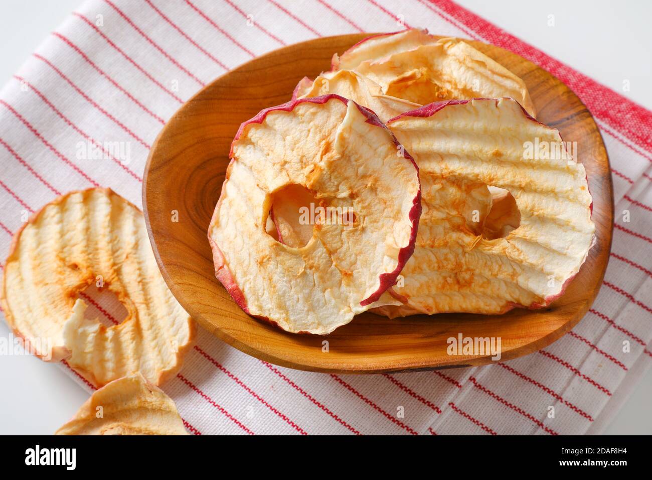Bowl of dried apple slices - apple chips or rings - on striped tea towel Stock Photo