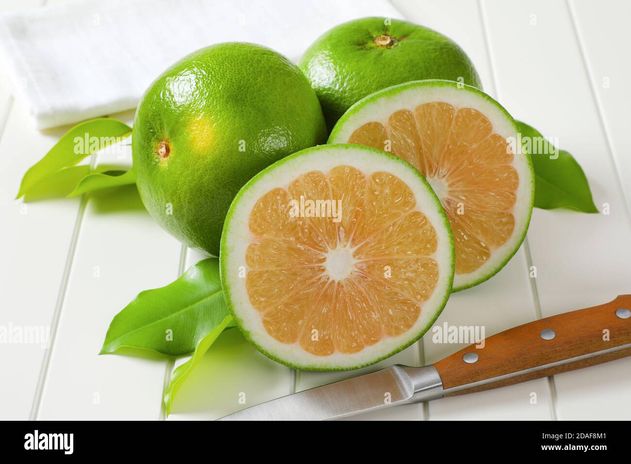 Sweetie fruits (green grapefruits, pomelits) - two whole fruits and slices Stock Photo