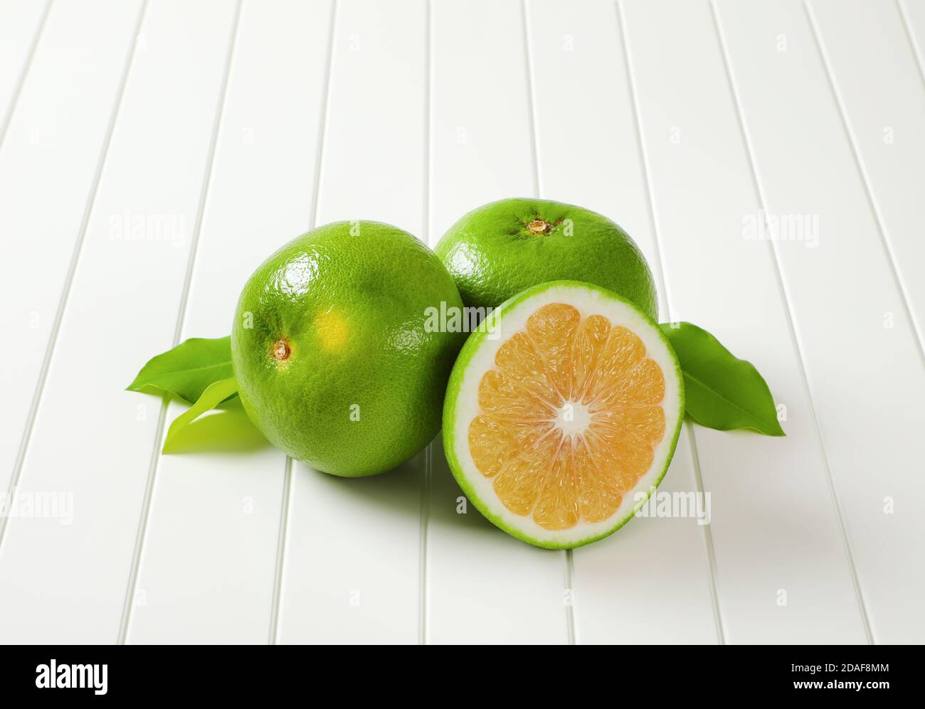 Two and a half sweetie fruits (green grapefruits, pomelits) and leaves Stock Photo