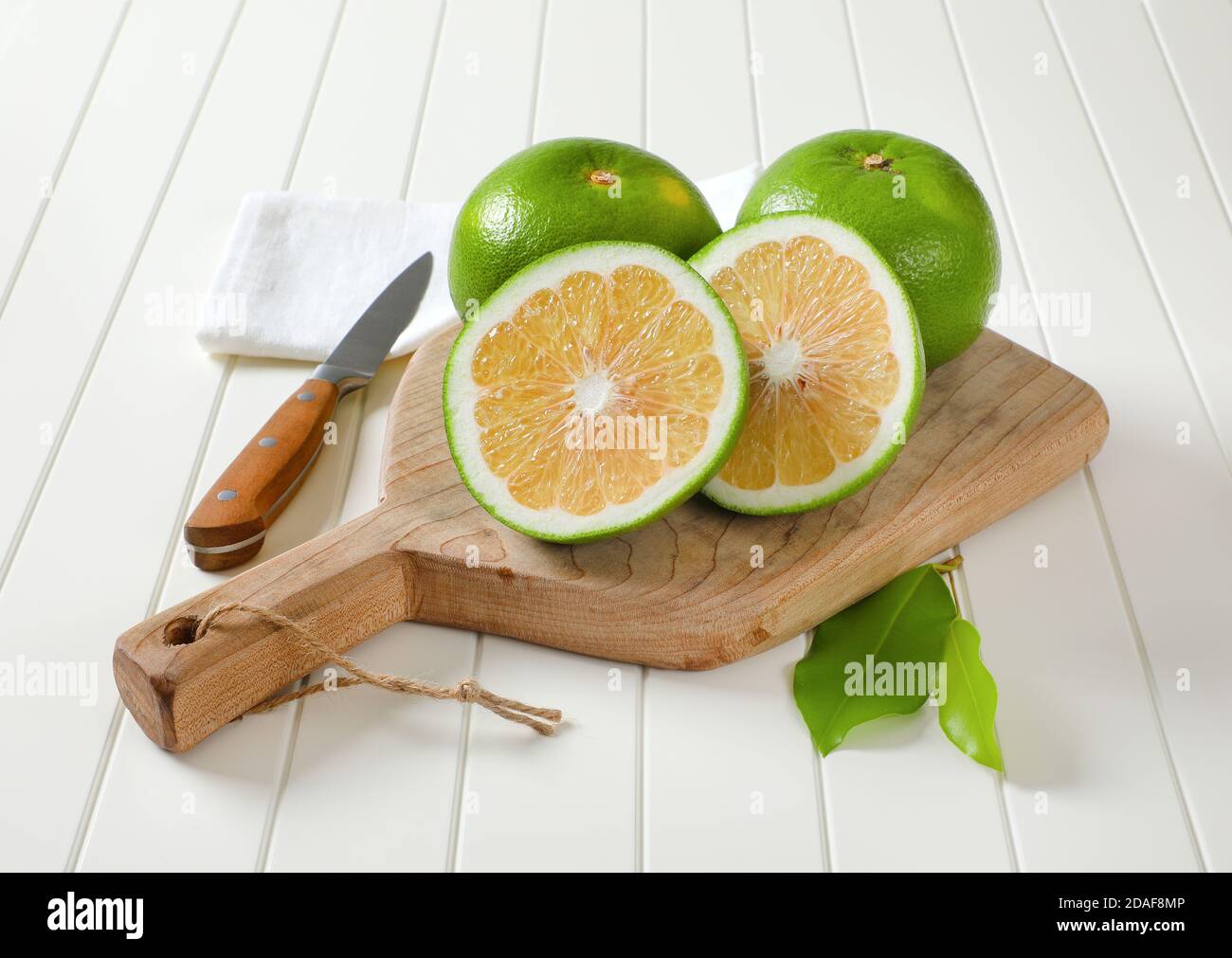 Sweetie fruits (green grapefruits, pomelits) - two whole fruits and slices - on cutting board Stock Photo