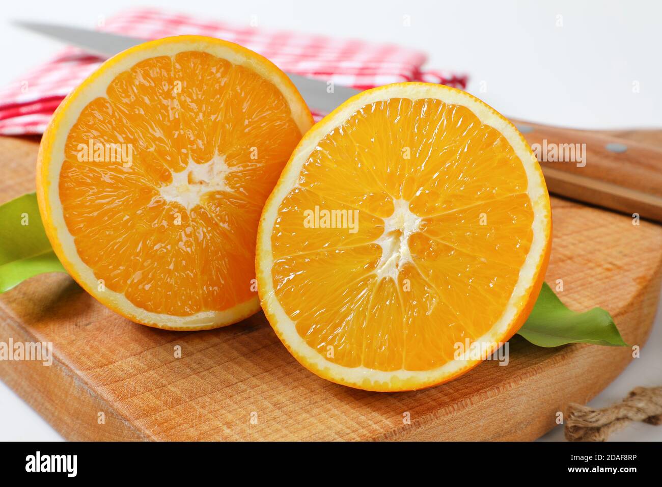 Two fresh orange halves on cutting board Stock Photo