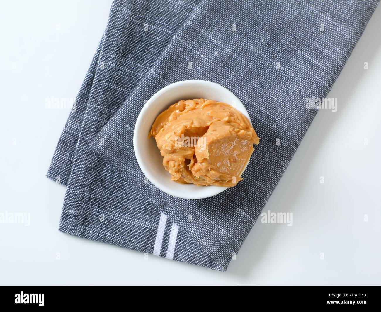 Bowl of crunchy peanut butter on gray napkin Stock Photo