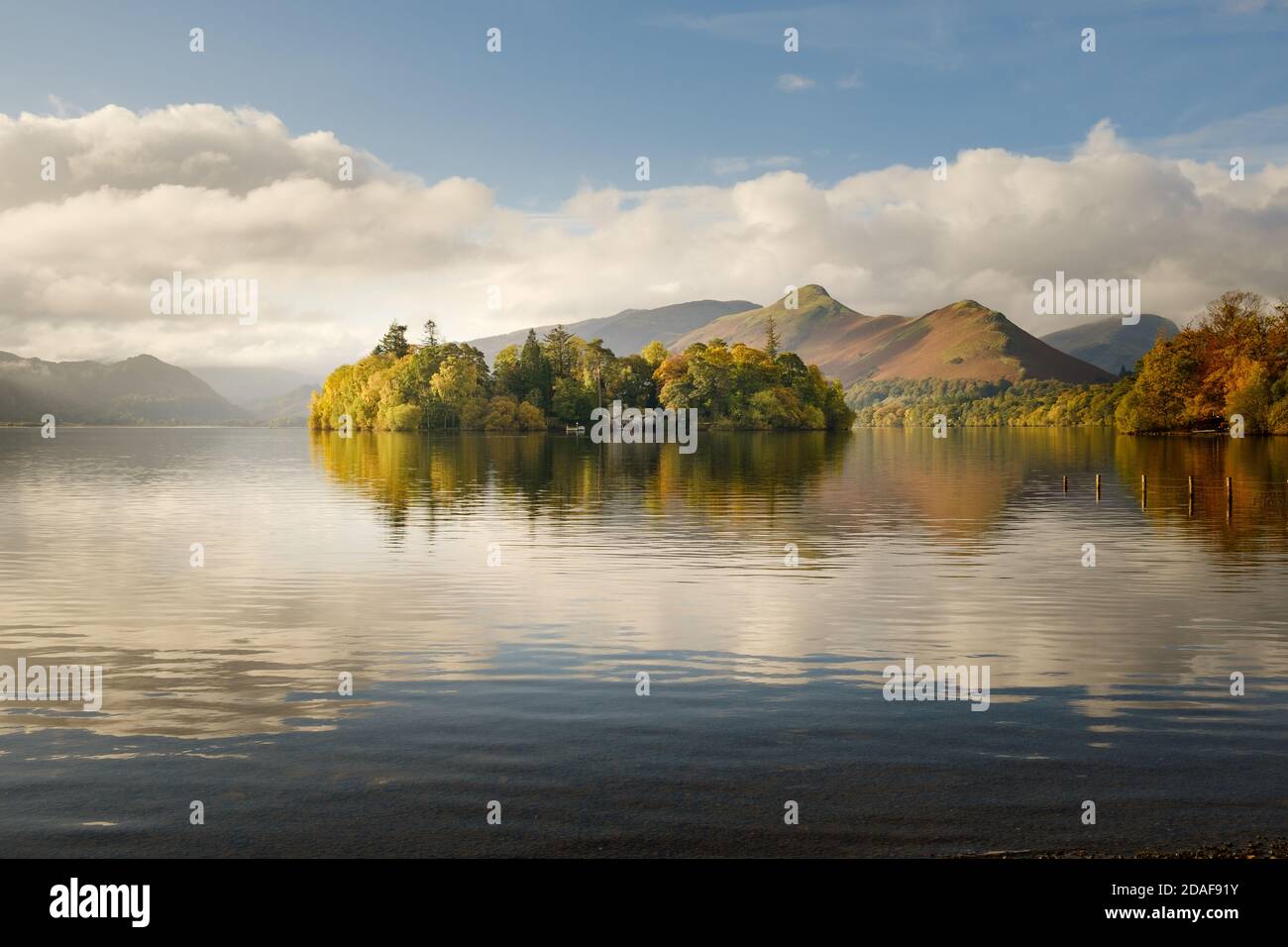 Lake District autumn landscape. Reflections of autumnal colour on Derwent Isle an island in Derwent Water  by Keswick in Cumbria Stock Photo