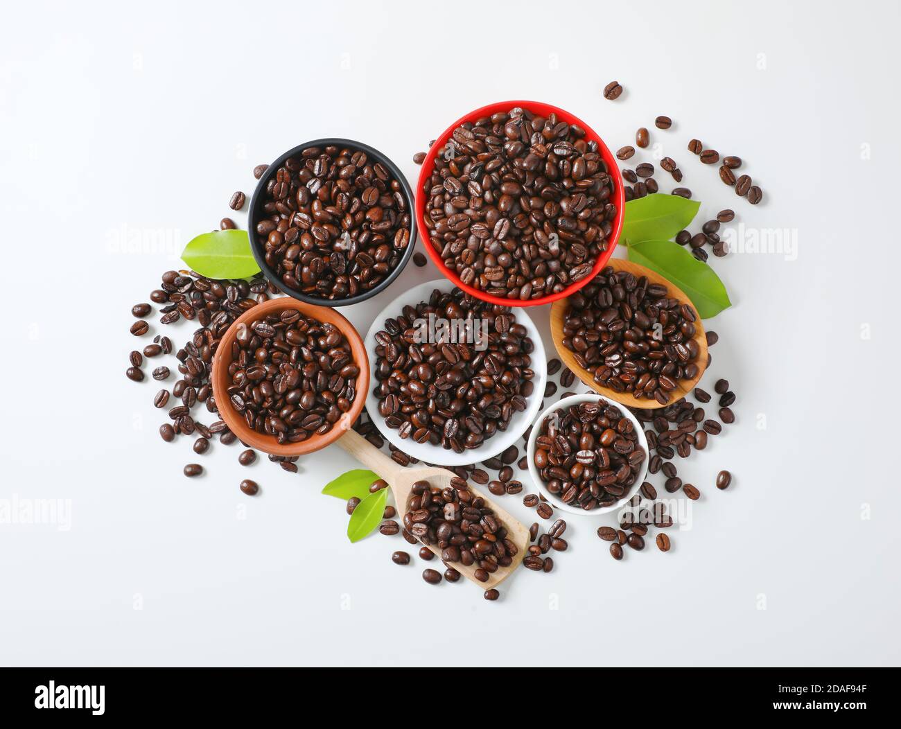 Roasted coffee beans in various bowls, on plate and wooden scoop Stock Photo