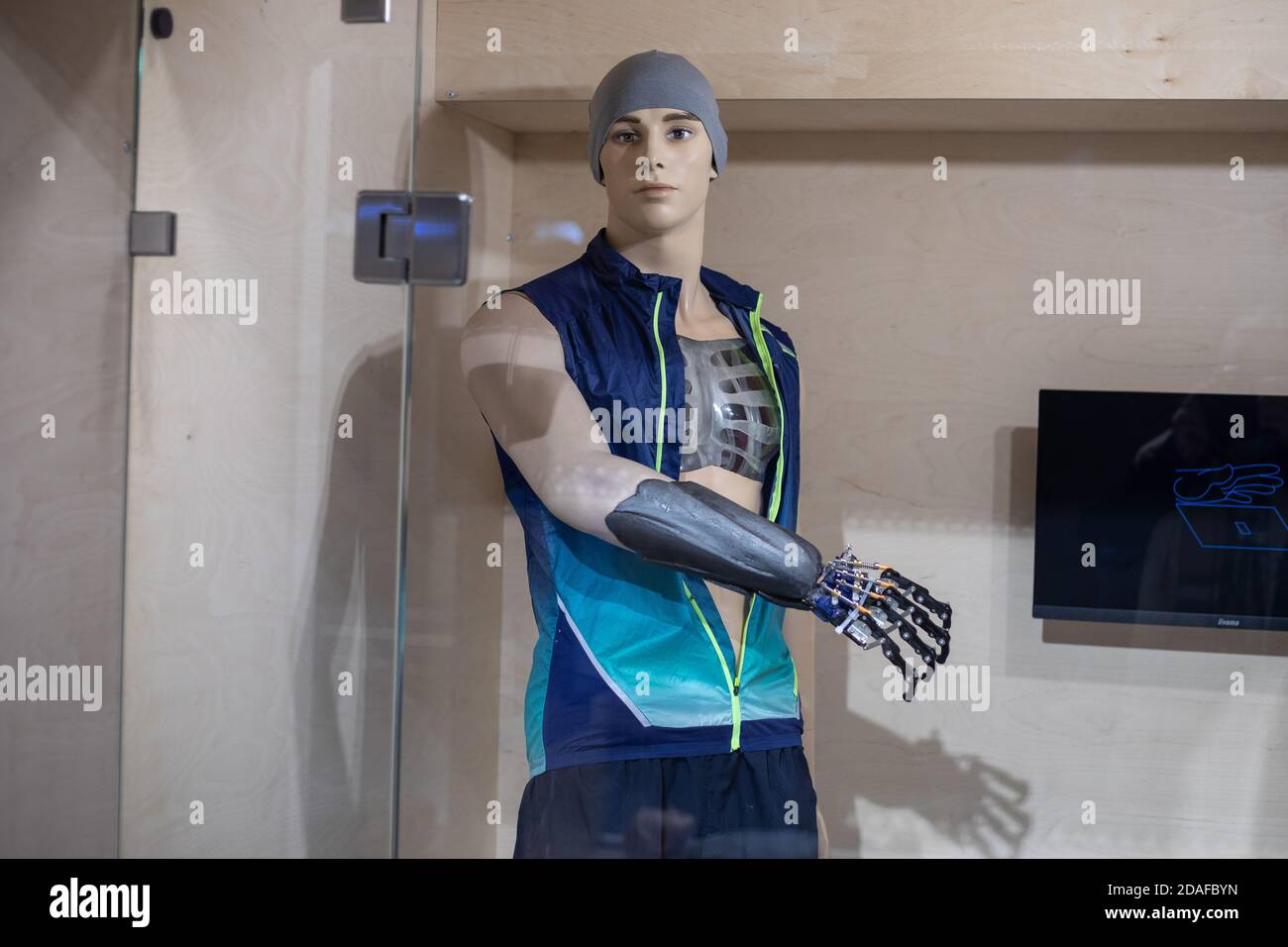 A mannequin in the form of a young man in sportswear with a prosthetic arm behind glass. Demonstration of new technologies in prosthetics. Robotic Stock Photo