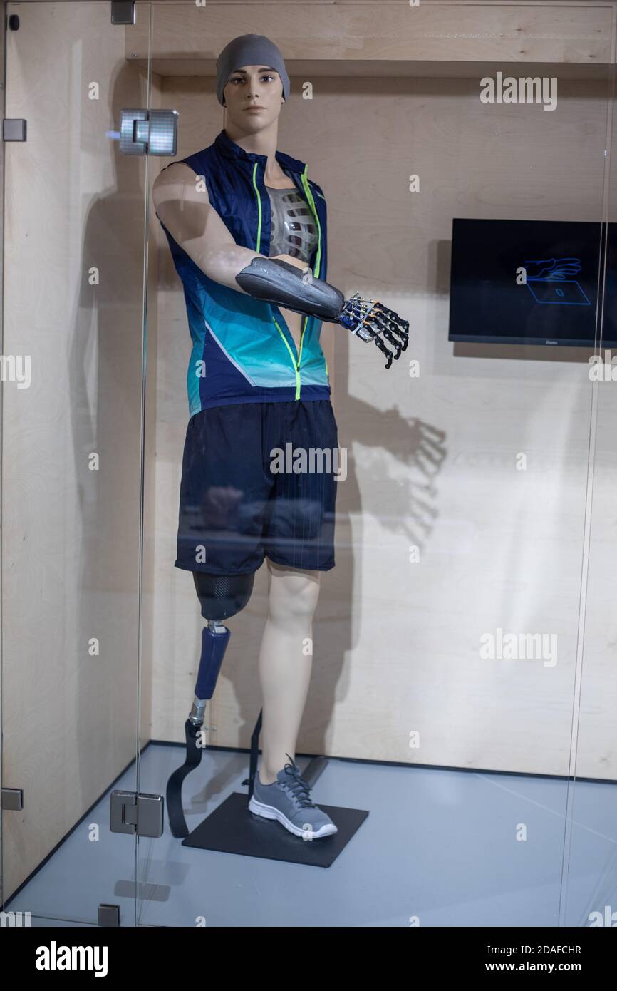 A mannequin in the form of a young man in sportswear with a prosthetic arm and leg behind glass. Demonstration of new technologies in prosthetics Stock Photo