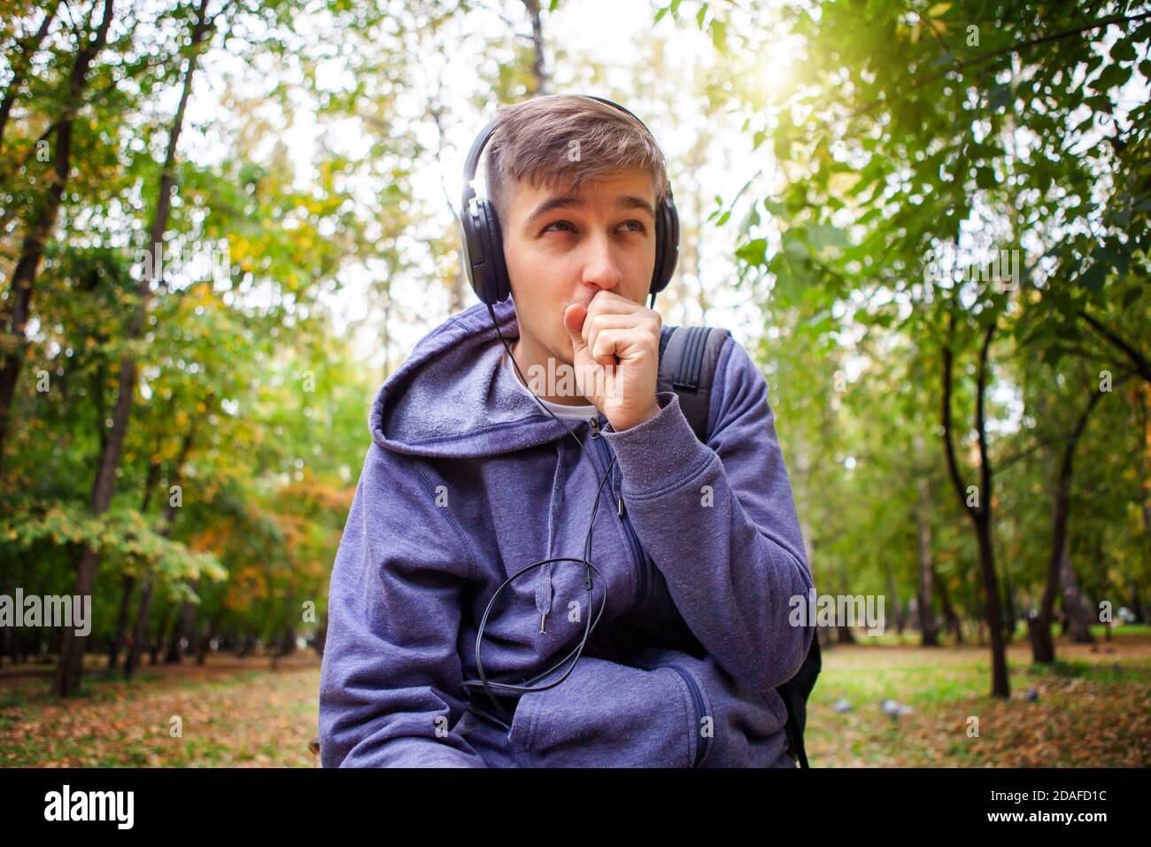 Frozen Young Man in Headphones listen to the Music in the Autumn Forest Stock Photo