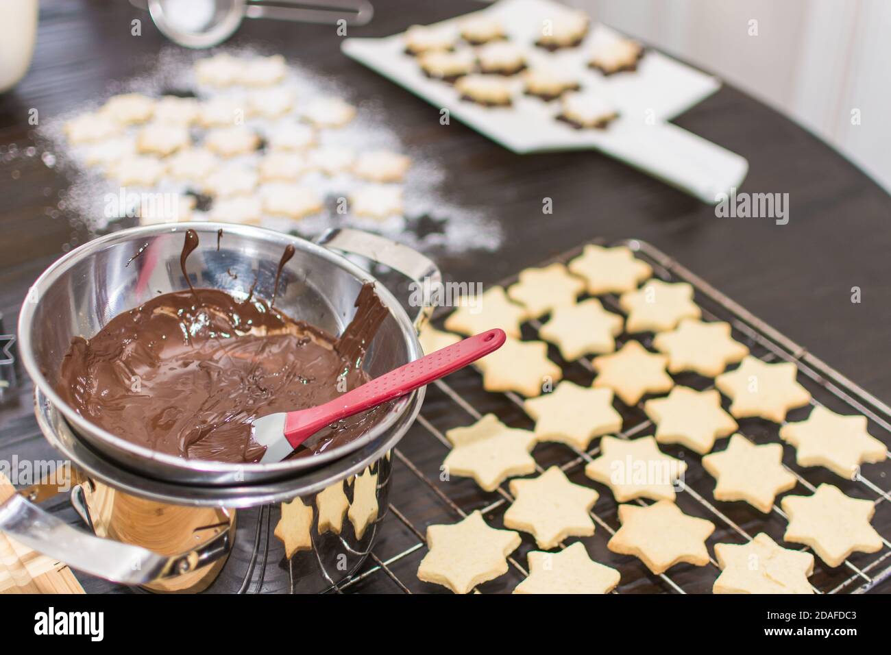 In the time before Christmas, cookies are baked at home in a star shape. Shortcrust pastry stars are covered with chocolate and sprinkled with powdere Stock Photo