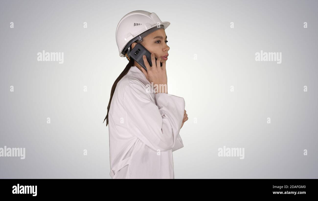 Female science engineer making a call while walking on gradient Stock Photo