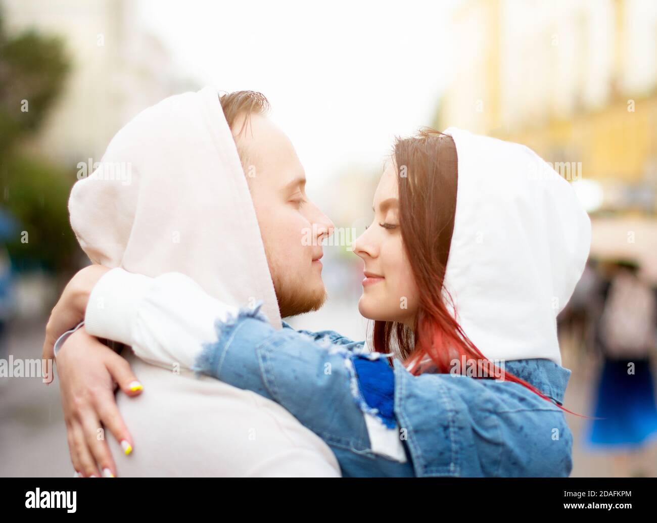 Side view of a young happy couple in love, men and women in hoods in the summer on the street.  Stock Photo