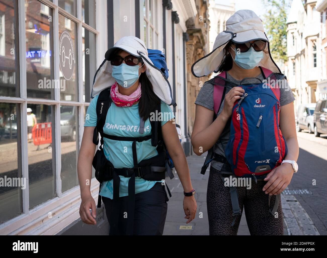 Two tourists dressed in Legionairre's hats and face masks, walk through Cambridge city centre during the 2020 COVID 19 pandemic Stock Photo