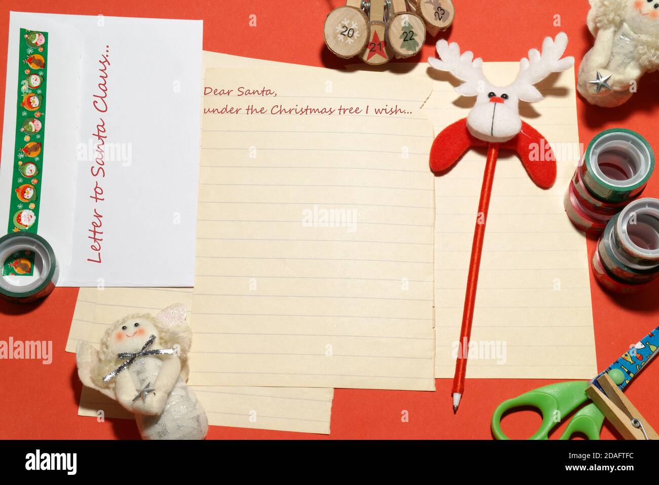 Christmas greeting card or letter to Santa Claus, with some decorations, pen and envelope on the red background. Maybe your wish will come true... Stock Photo