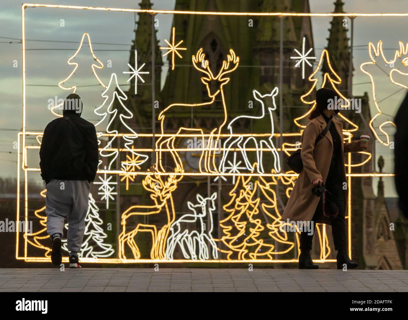 Christmas decorations have been erected by the Bullring in Birmingham city centre, UK, and people are seen walking by during the lockdown Stock Photo