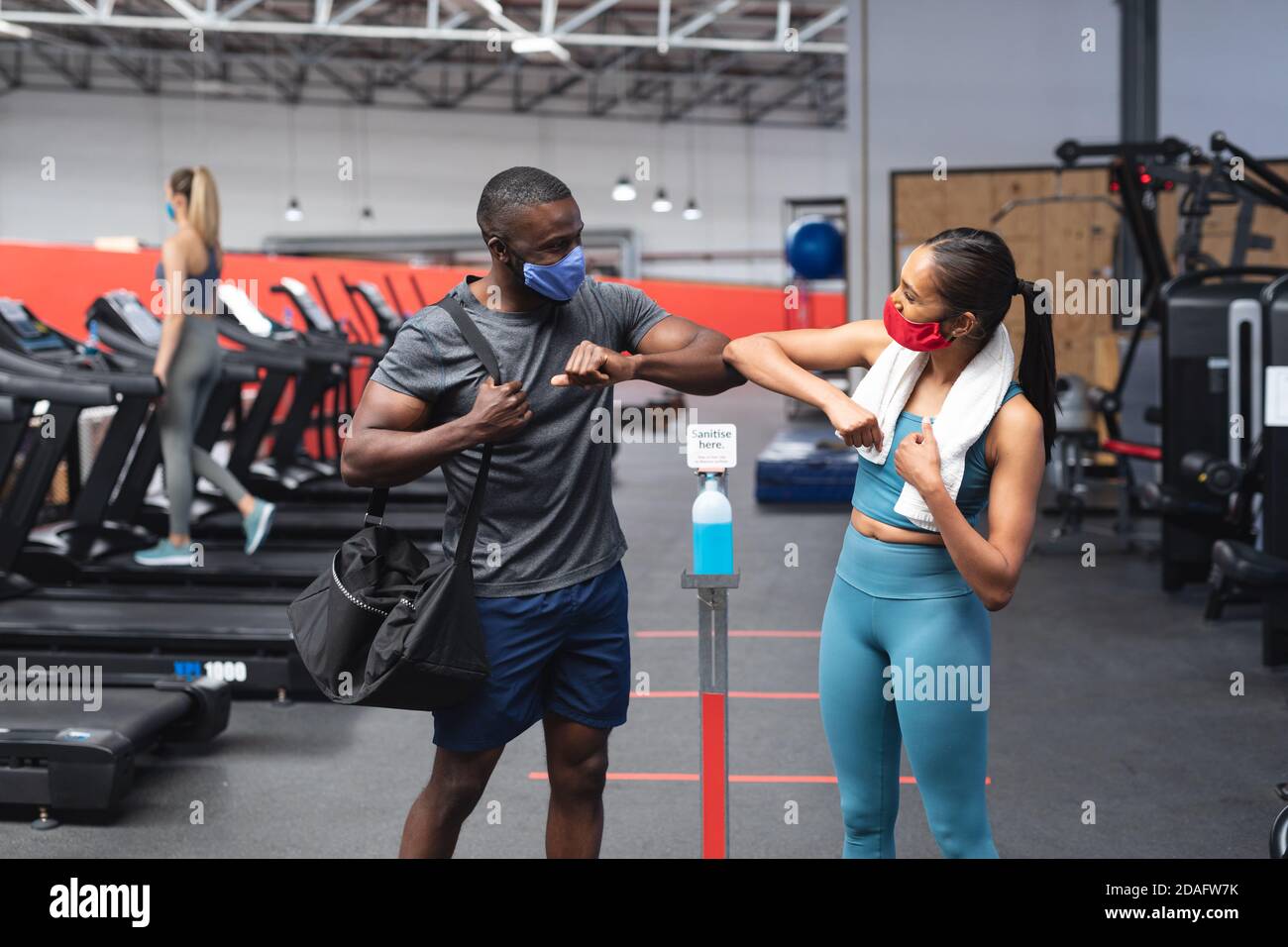 Fit african american man and fit caucasian woman greeting each other by touching elbows in the gym Stock Photo