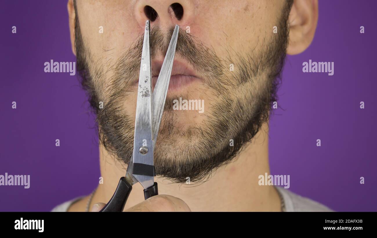 Handsome young guy trims his beard with scissors. Stock Photo