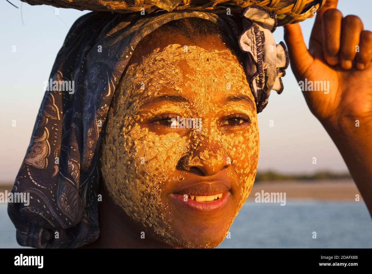 Woman (faced painted with clay as sunblock) carrying basket, Morondava, Madagascar Stock Photo