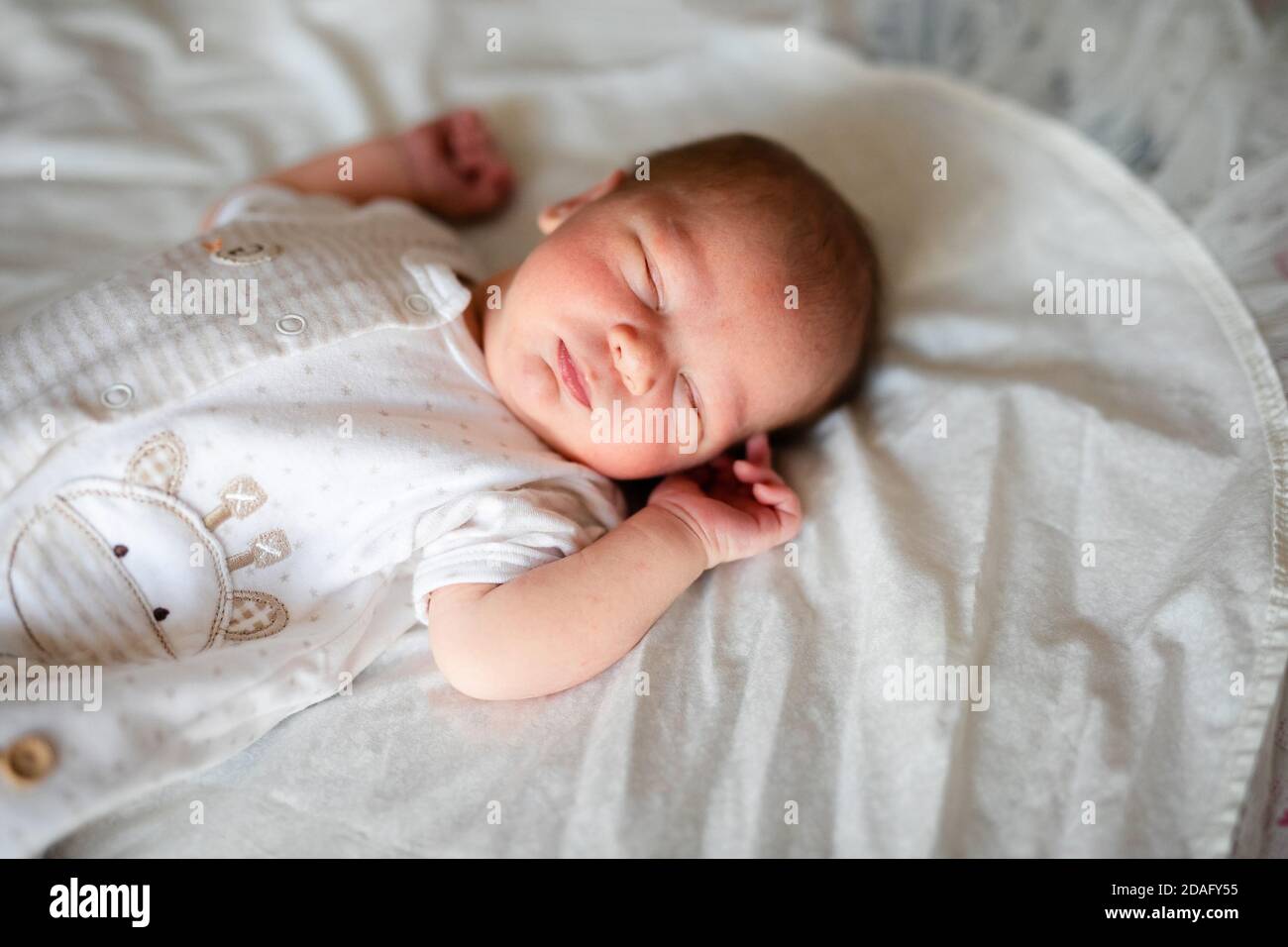 Newborn baby boy in bed. New born child in white bodykit lying in light ...