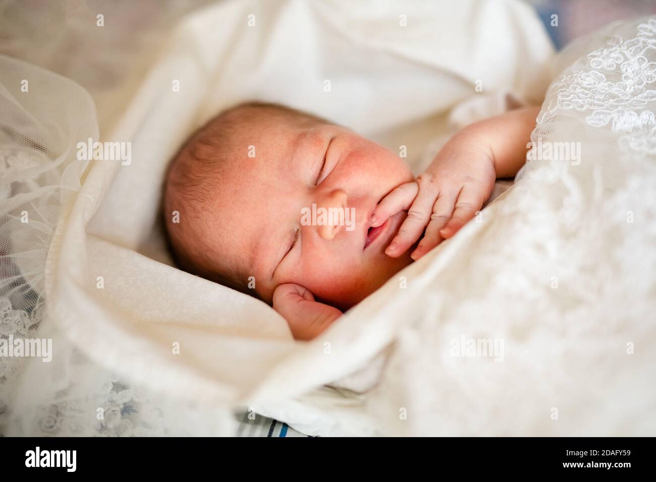 Newborn baby boy in bed. New born child in white bodykit lying in light cradle. Children sleep