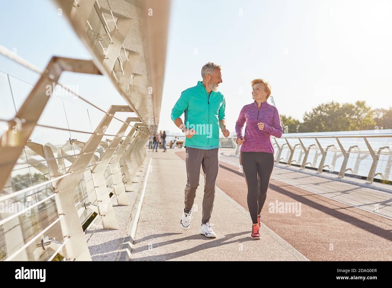 Morning activity. Full length shot of active mature family couple in sportswear smiling at each other while jogging together on a sunny morning Stock Photo