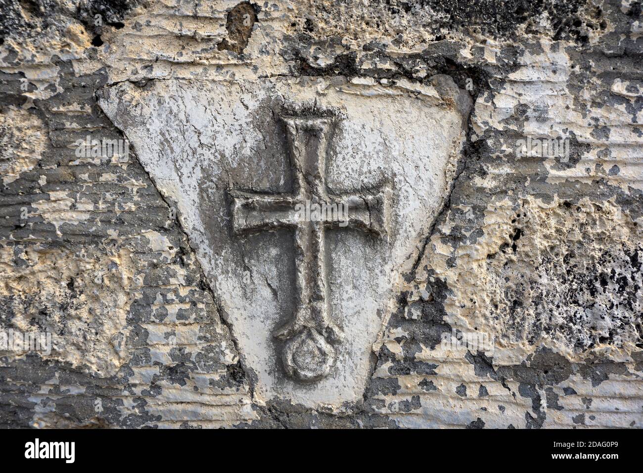 Ancient Greek Christian cross on the old stone wall of the temple. Stock Photo