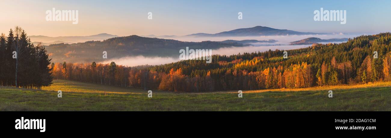 misty landscape at sunset, mountains rising from clouds of fog in the background, clear sky - mountain Klet, Czech republic Stock Photo