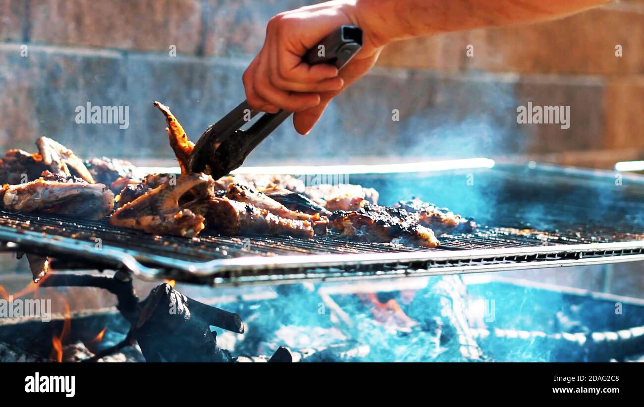 close up on a man hand as he cooking meat on the barbecue, Chef hand putting some meat skewers on the grill Stock Photo