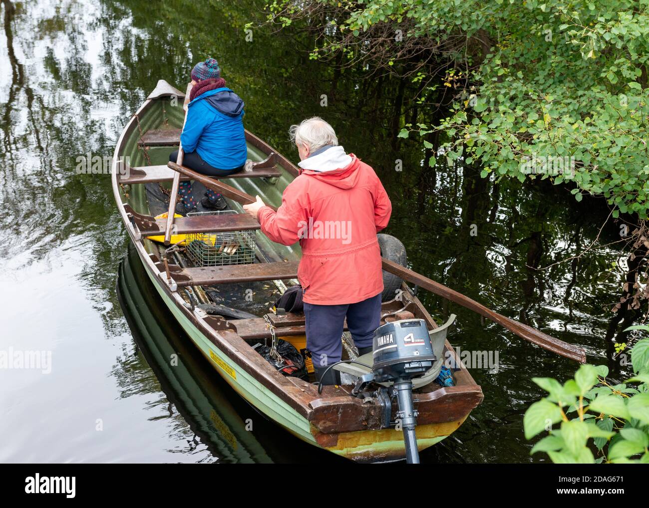 Senior couple paddling on a fishing row boat or clinker boat in small lake inlet in Killarney National Park, County Kerry, Ireland, Europe Stock Photo