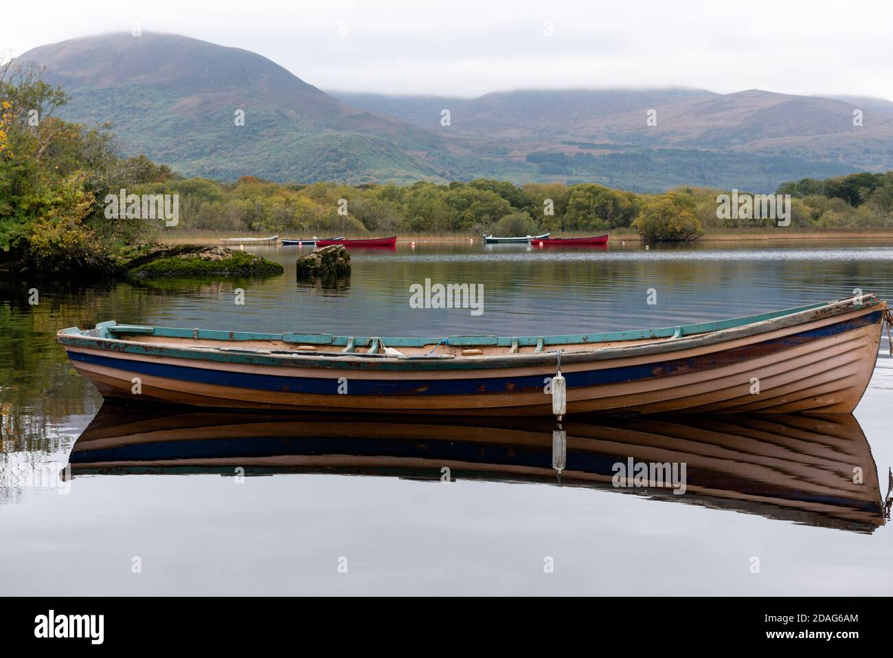 Fishing boat on calm Lough Leane lake with moored fishing boats and Eagle's Nest Mountain in Killarney National Park, County Kerry, Ireland, Europe. Stock Photo