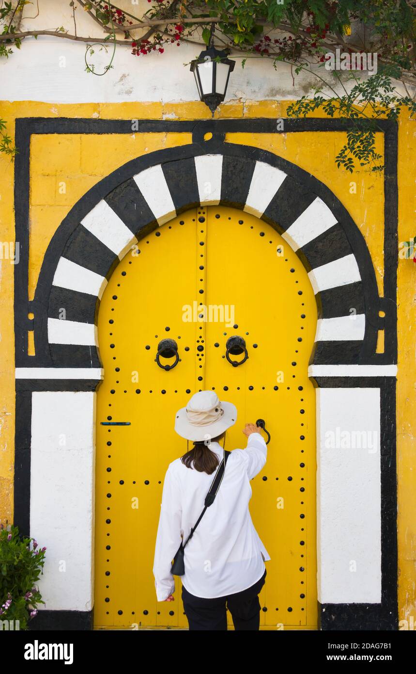 Tourists knocking at yellow door, Sidi Bou Said, Tunis, Tunisia Stock Photo