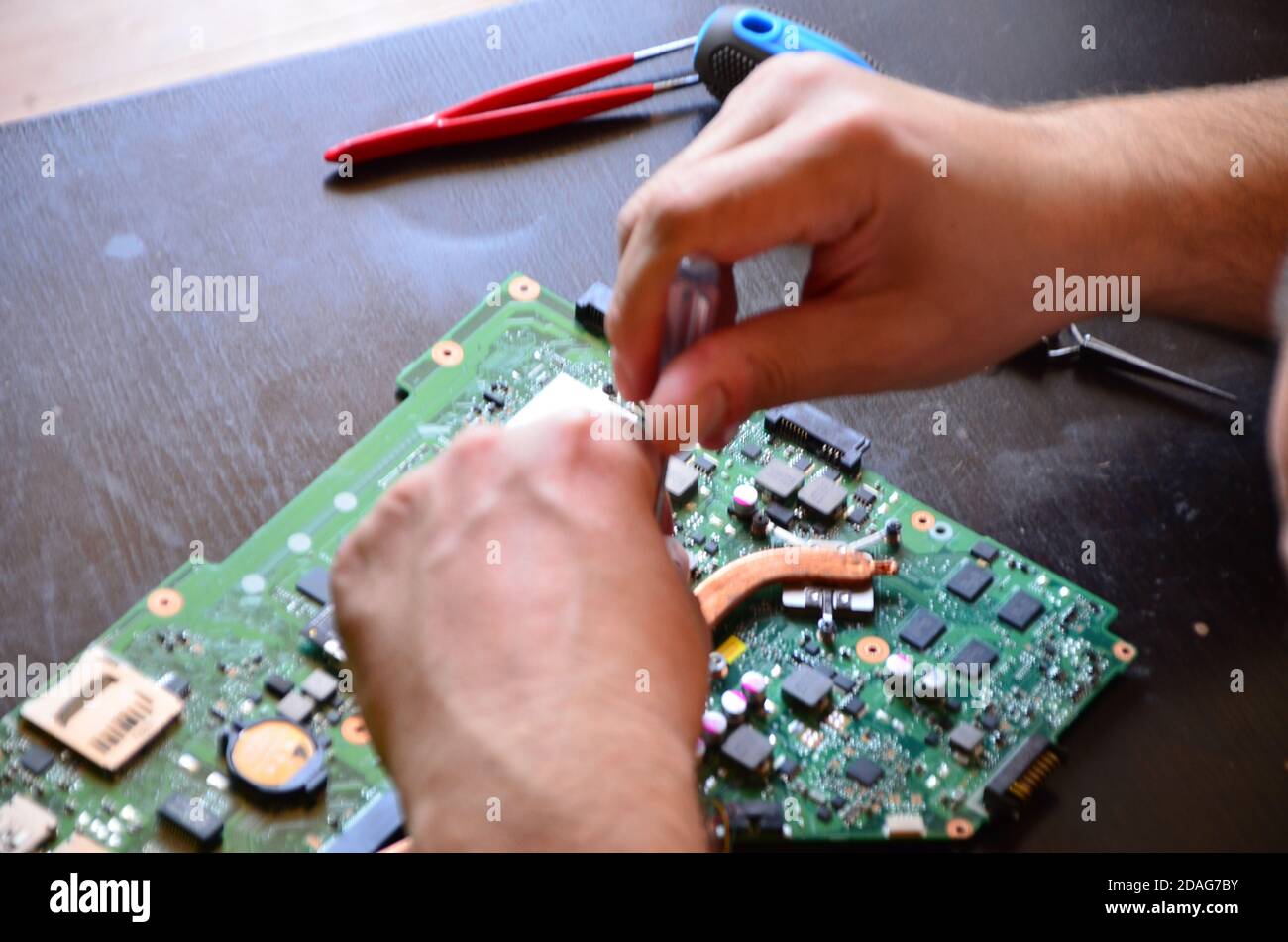 The man hand of the technician assembling inside of tablet by screwdriver in the lab. the
